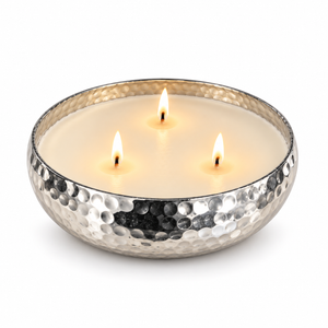A hammered silver metal candle bowl filled with white wax and three wicks, placed on a white background.