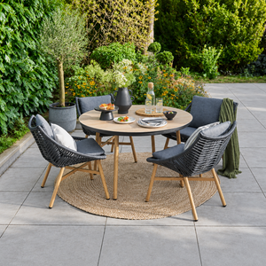 Outdoor patio set with round table and chairs on a patio with greenery in the background