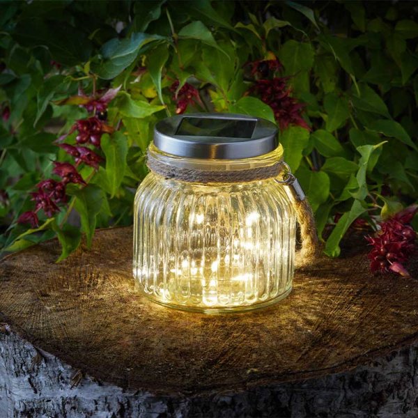 Solar-powered jar light on a wooden stump with greenery in the background