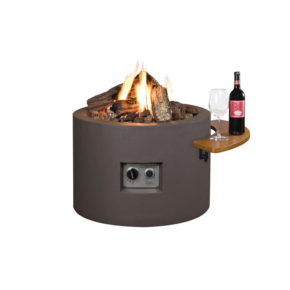 A round grey Cocoon fire pit with a curved composite structure, featuring an electric ignition system, ceramic logs, and lava stones inside, with a control panel on the front.