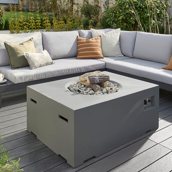Outdoor patio setup with a fire pit table and sectional sofa with cushions.