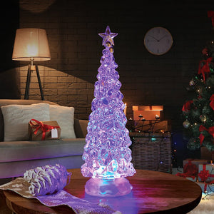 Ice effect LED Christmas tree with a star topper glowing purple on a wooden table beside a festive fireplace.