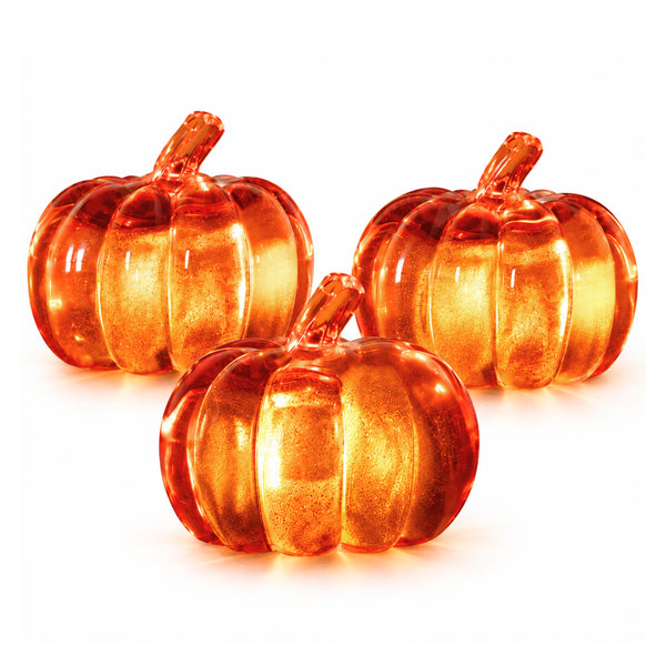 Three translucent orange glass pumpkins with ribbed textures and stems, arranged on a clean white background.