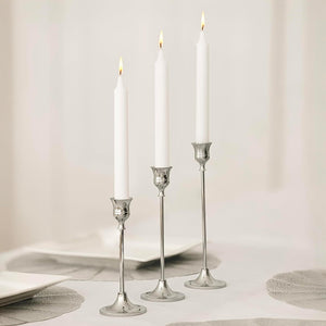 Three silver candlestick holders with white taper candles