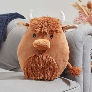 Plush toy Highland cow on a gray couch with a neutral background