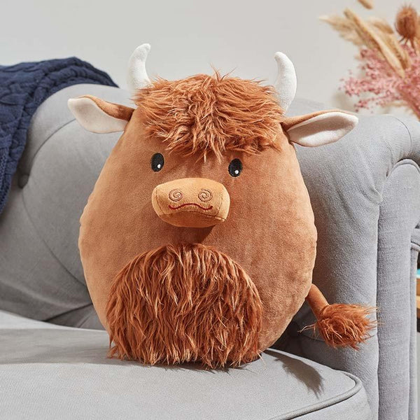 Plush toy Highland cow on a gray couch with a neutral background