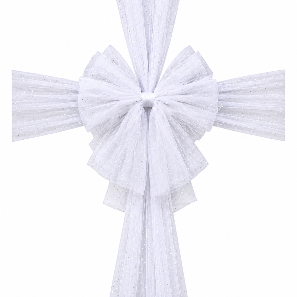 A large white tulle bow and matching hanging tulle decoration displayed on a wooden front door, with a stone wall, wall lantern, potted plants, and a doormat visible.