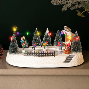 Christmas-themed miniature scene with trees, Santa Claus, and lights on a dark background