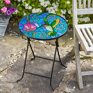 Colorful stained glass table with hummingbird and flower design on a stone patio.