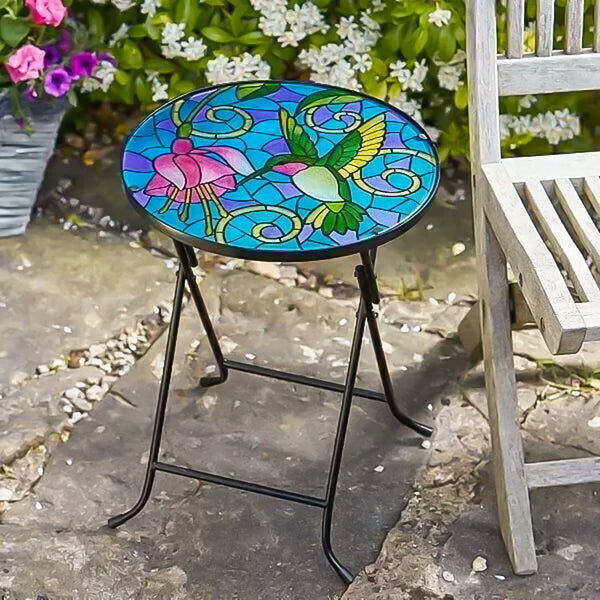 Colorful stained glass table with hummingbird and flower design on a stone patio.