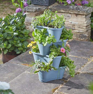 Stacked blue tiered planter with plants on a stone surface