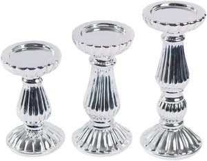 Three silver metallic candle holders of different sizes arranged side by side on a plain white background.