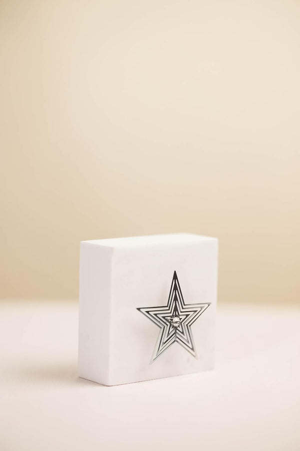 White cube-shaped box with a star design on a beige background