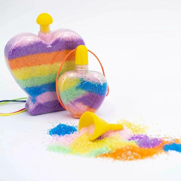 Colorful sand toy with heart-shaped container and sand spilling out on a white background