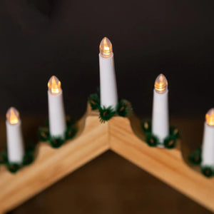 Decorative candles on a wooden shelf with a dark background