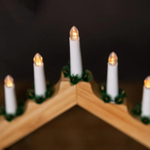 Decorative candles on a wooden shelf with a dark background