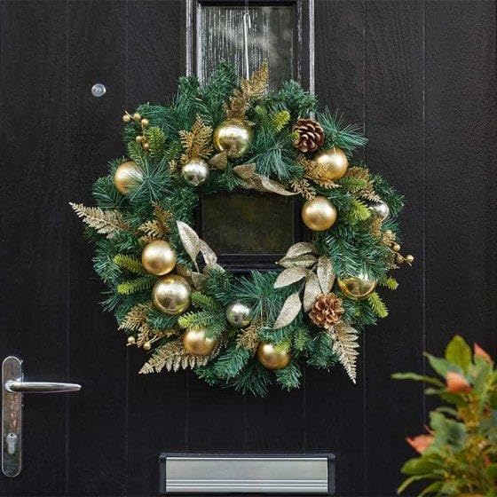 Decorative Christmas wreath with gold ornaments on a black door
