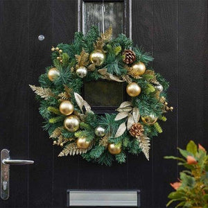 Decorative Christmas wreath with gold ornaments on a black door