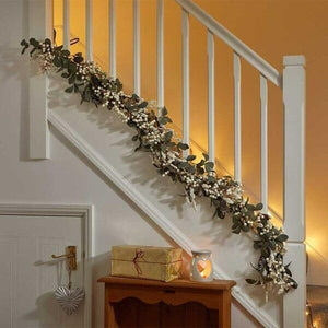 Decorative garland with lights on a staircase railing, with a warm glow.