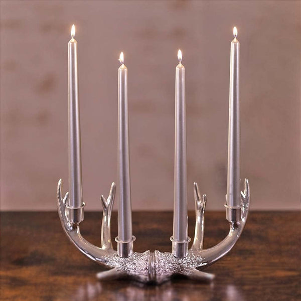 Silver candle holder with five lit candles on a wooden surface.