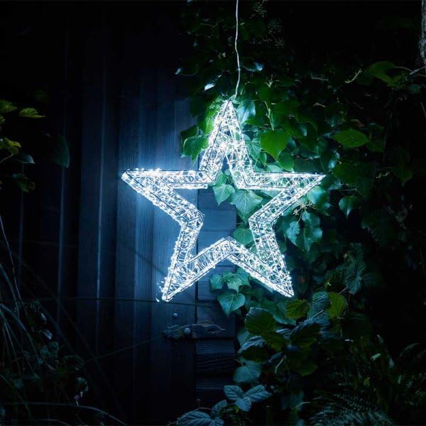 Decorative LED star hanging among green leaves at night