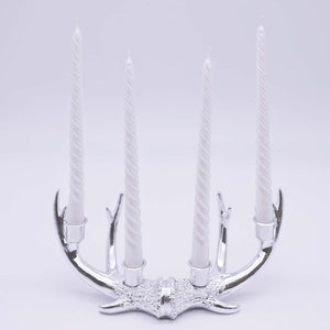 Silver antler-shaped candle holder with four candles on a light gray background