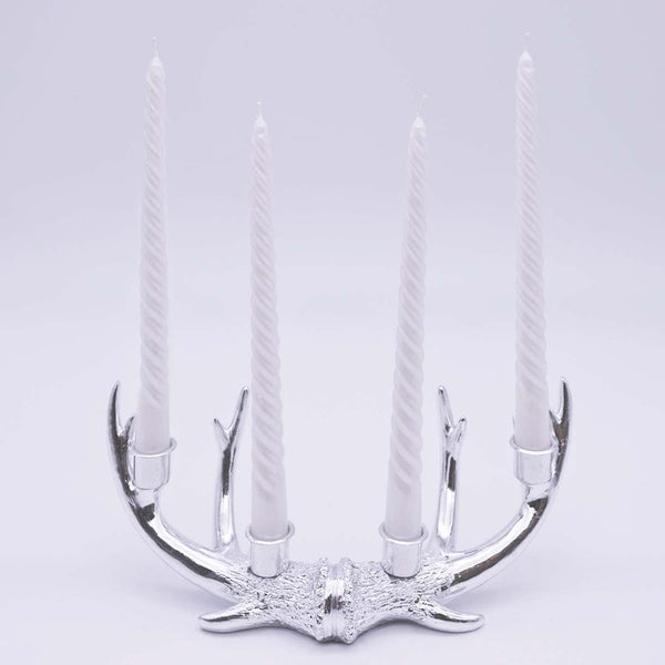 Silver antler-shaped candle holder with four candles on a light gray background