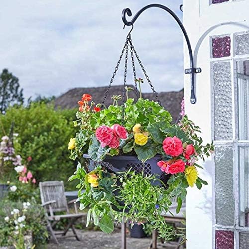 Hanging flower basket with pink and yellow flowers attached to a metal bracket on a house exterior.