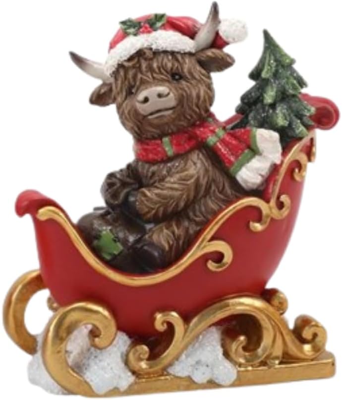 Decorative figurine of a Highland cow in a sleigh with a Christmas tree, on a surface with a blurred background.