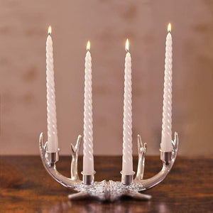 Candle holder with four lit candles on a wooden surface