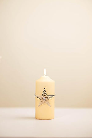 Beige candle with a star design on a beige background