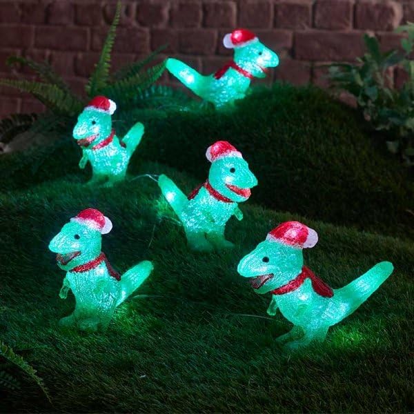 Set of four green dinosaur lights with red Santa hats on grass