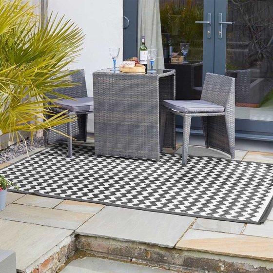 Outdoor patio setup with wicker furniture and a geometric patterned rug.