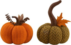 Two knitted pumpkins, one orange and one green with a leaf, on a white background.