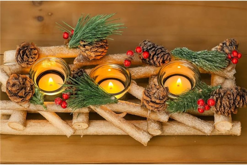 Decorative arrangement with candles, pine cones, and greenery on a wooden surface.