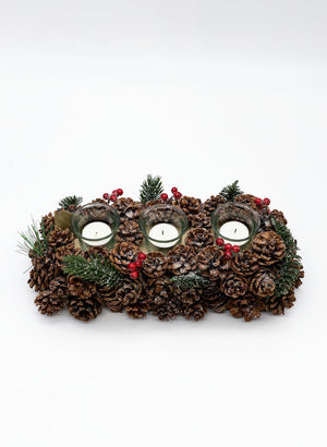 Decorative candle holder with pinecones and candles on a white background