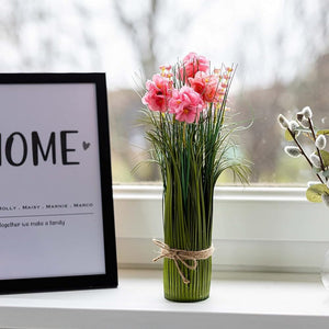 Vase with pink flowers on a windowsill next to a framed picture with 'HOME' text.
