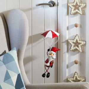 Decorative Christmas ornament of a Santa Claus with an umbrella hanging on a door.