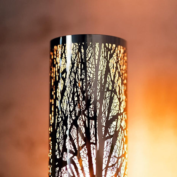 Decorative lamp with tree silhouette design against a warm gradient background