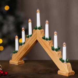 Wooden advent calendar with lit candles against a blurred Christmas tree background