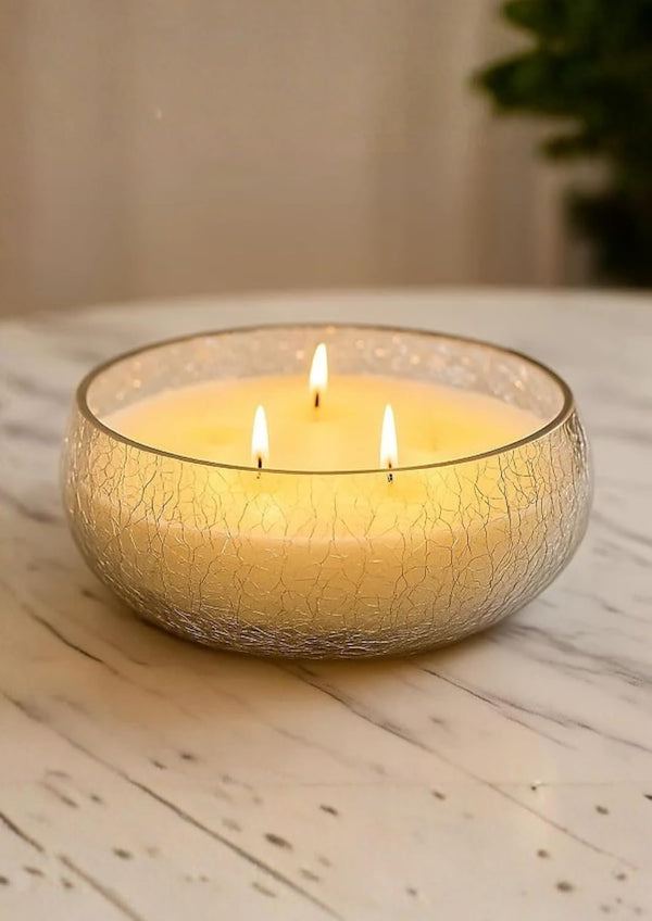 Three-wick candle in a textured glass holder on a wooden surface