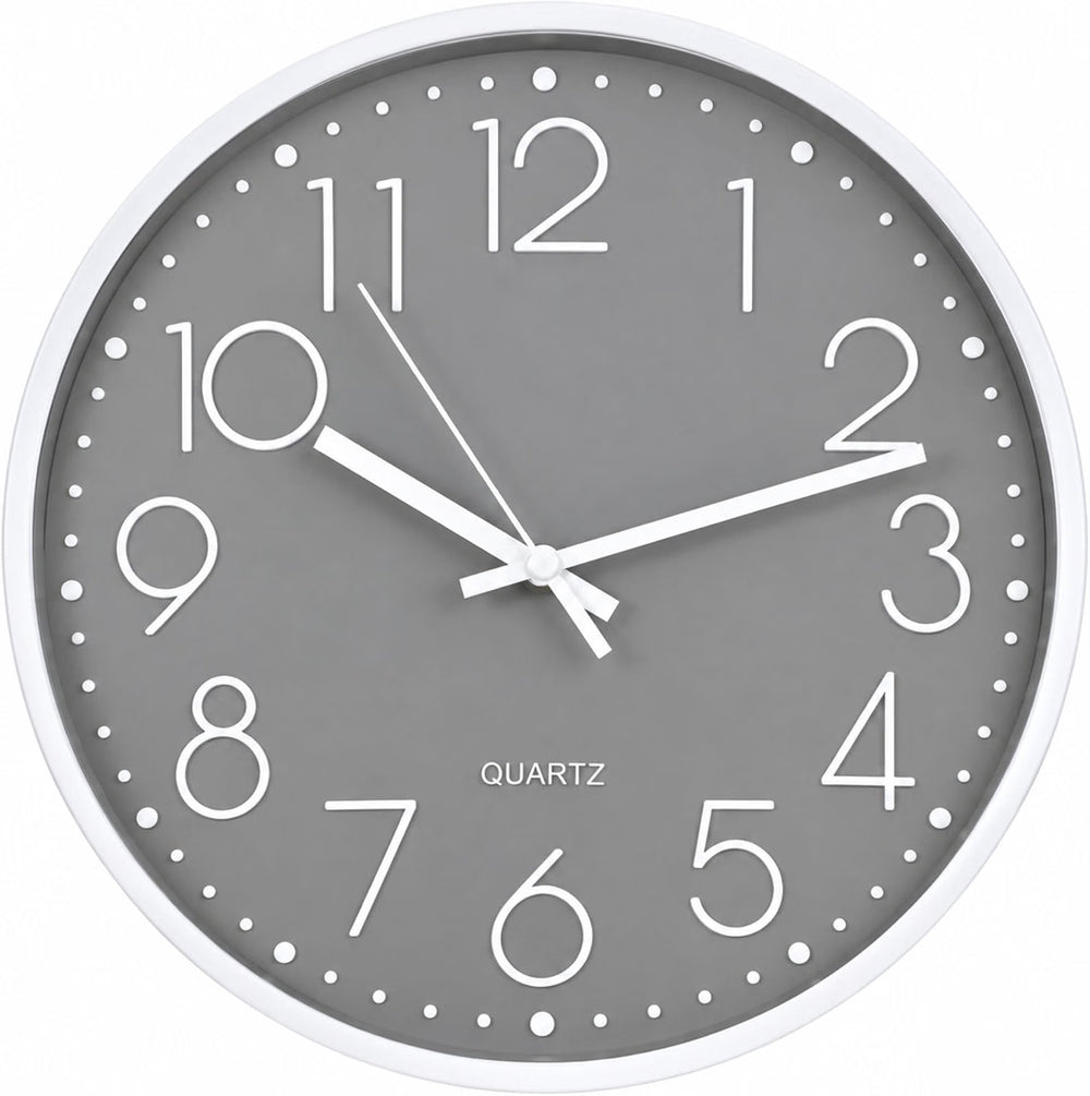 A round gray quartz wall clock with a white frame and white numerals, mounted on a light beige wall above a gray sofa in a modern living room setting.
