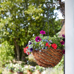 Hanging flower basket with colorful flowers against a blurred green garden background