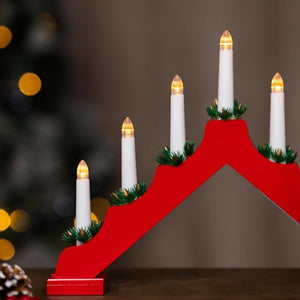 Red Advent calendar with white candles against a blurred Christmas tree background