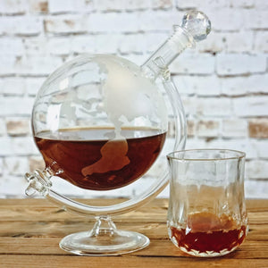 Globe-shaped glass with liquid on a wooden surface, with blurred brick wall as background.