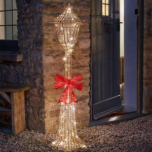 Decorative outdoor light with a red bow attached to a stone wall.