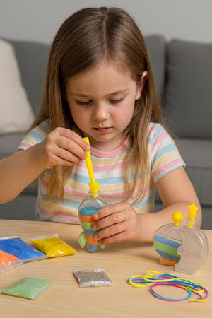 Young girl playing with colorful sand toys on a table.