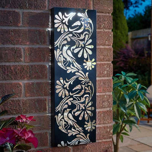 Decorative metal wall art with floral patterns on a brick wall