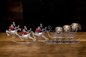Decorative sleigh with reindeer and candle holders on a wooden surface