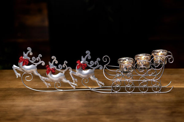 Decorative sleigh with reindeer and candle holders on a wooden surface